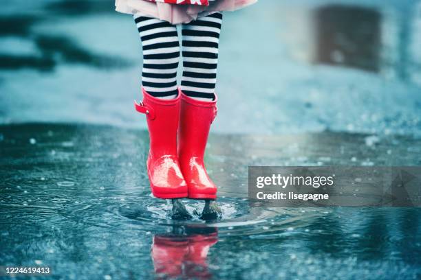 4 ans petite fille sautant dans la flaque d’eau - bottes photos et images de collection