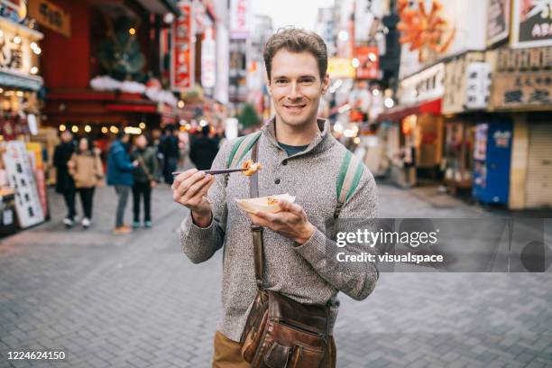 tourist trying the best street in osaka - japanese food stock pictures, royalty-free photos & images