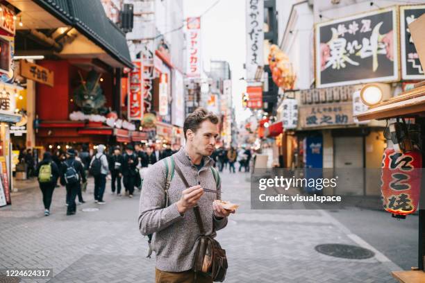 tourist trying the best street in osaka - takoyaki stock pictures, royalty-free photos & images