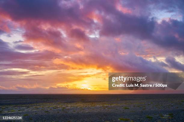 sunset with dramatic sky over land in volcanic area, kalfafell, eastern region, iceland - kalfafell iceland stock pictures, royalty-free photos & images