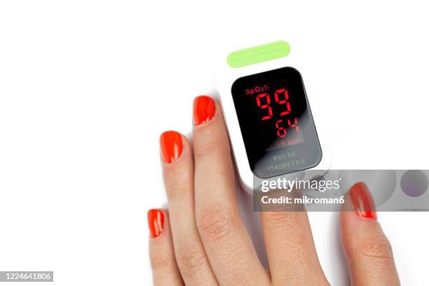 a woman checking her heart rate and oxygenation level on her finger - hypochondria stock pictures, royalty-free photos & images