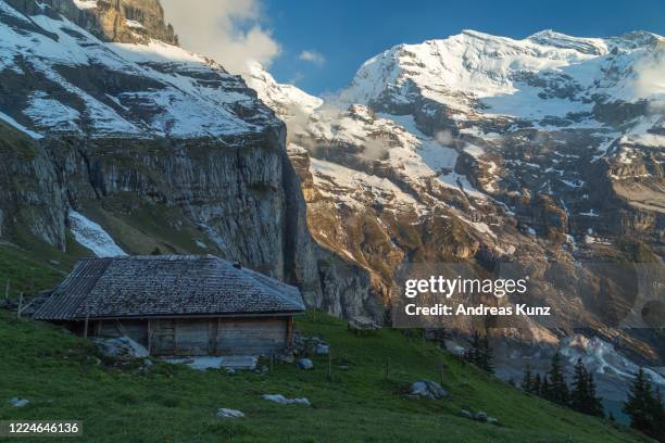 alte berghütte bei sonenuntergang in der nähe des kristallblauen gebirgssee oeschinensee berner oberland in der schweiz - alpen berghütte bildbanksfoton och bilder