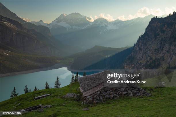 zum sonnenuntergang der ausblick auf den kristallblauen gebirgssee oeschinensee mit sonnenstrahlen im berner oberland in der schweiz - sonnenstrahlen stock pictures, royalty-free photos & images