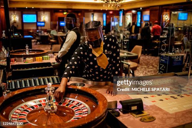 Croupier wearing a face mask and a face shield spins the ball of a roulette table at the Montecasino complex in Johannesburg, on July 3, 2020. - The...