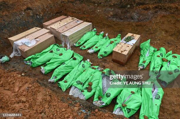 The bodies of miners in wooden coffins and wrapped up in bags are pictured in a mass grave before being buried, following a deadly landslide in an...