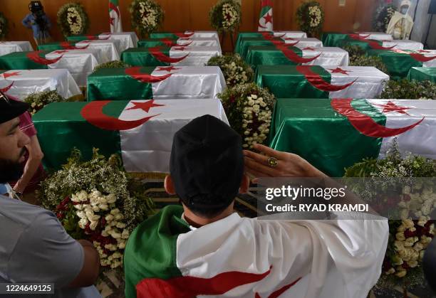 An Algerian man pays respect in front of the national flag-draped coffins containing the remains of 24 Algerian resistance fighters decapitated...