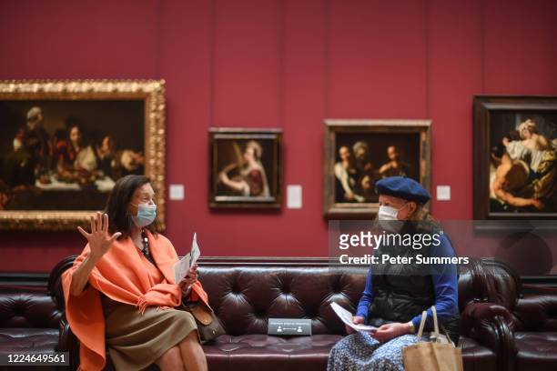 Two women are seen wearing masks while viewing paintings at the National Portrait Gallery during a press preview ahead of the gallery's reopening on...