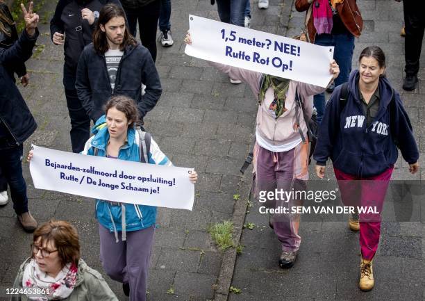 People hold banners during a protest of a dozen persons against COVID-19 measures in Park Oog in Al, in Utrecht, on July 4, 2020. - Deputy Chairman...