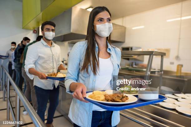 personas sociales distanciando y usando máscaras faciales mientras almorzaen en un buffet - comedor edificio de hostelería fotografías e imágenes de stock
