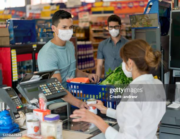 man buying essentials at the grocery store during the quarantine and wearing a facemask - supermarket mask stock pictures, royalty-free photos & images