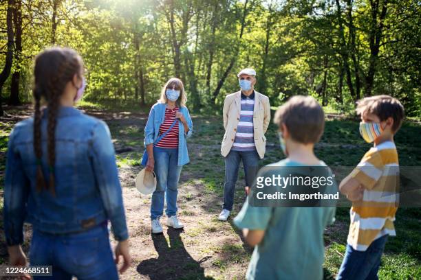grandparents and grandchildren meeting in park during covid-19 pandemic - social distancing stock pictures, royalty-free photos & images