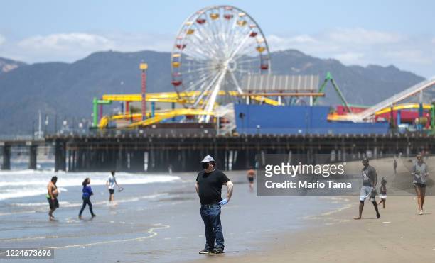 Man wears a face mask and gloves on Santa Monica beach on the day Los Angeles County reopened its beaches, which had been closed due the coronavirus...
