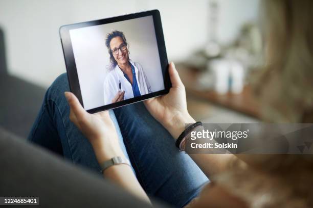 young woman having online meeting with female healthcare person - digital tablet stock pictures, royalty-free photos & images