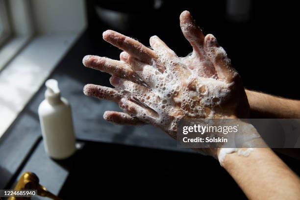 young man washing hands - händedesinfektion stock-fotos und bilder