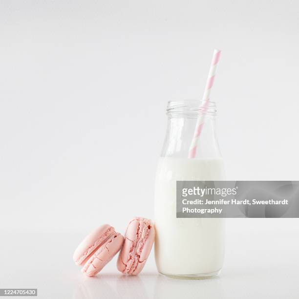 studio shot of personal milk bottle with pink and white straw with pink macarons - milk bottles stock pictures, royalty-free photos & images