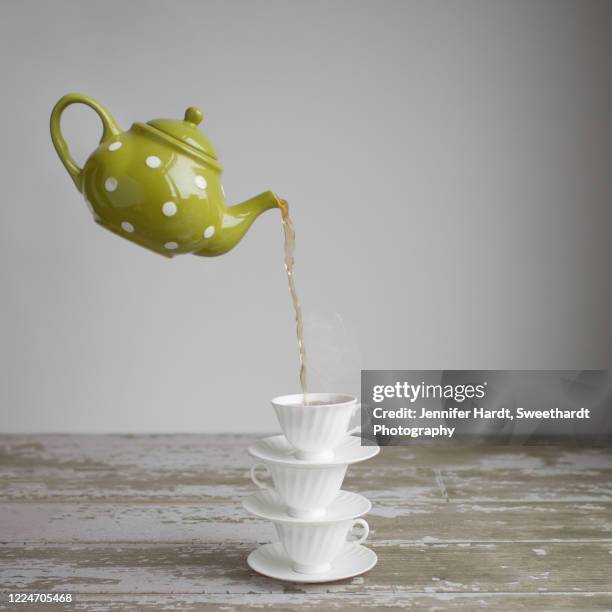 studio shot of a stack of 3 teacups with a floating teapot pouring tea - tea cup photos et images de collection