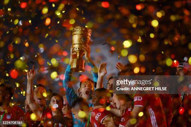 Bayern Munich's German goalkeeper Manuel Neuer raises the German Cup trophy as he and his teammates celebrate winning the final football match Bayer...