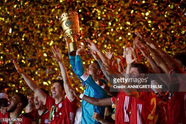 Bayern Munich's German goalkeeper Manuel Neuer raises the German Cup trophy as he and his teammates celebrate winning the final football match Bayer...