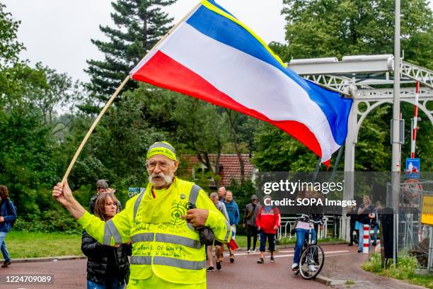 An old man wearing a reflecting jacket is seen holding a flag during the demonstrations. Police officers from the Mobile Unit in Lombok district,...