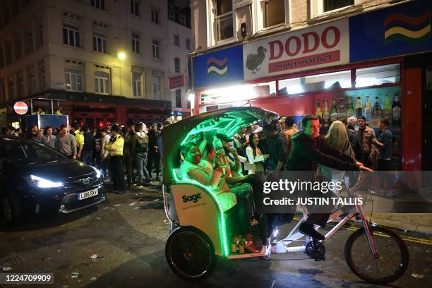 Woman in a pedicab smiles as she is conveyed through streets filled with revellers outside the bars in the Soho area of London on July 4 following a...