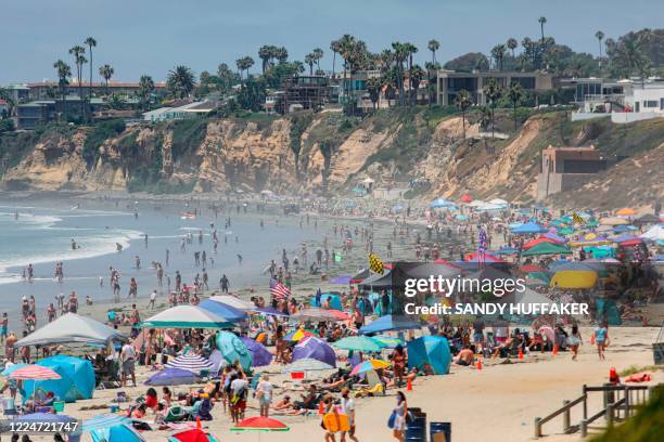 Beachgoers are seen along the shore in the Pacific Beach area of San Diego, California on July 4 amid the coronavirus pandemic. - Many beaches have...