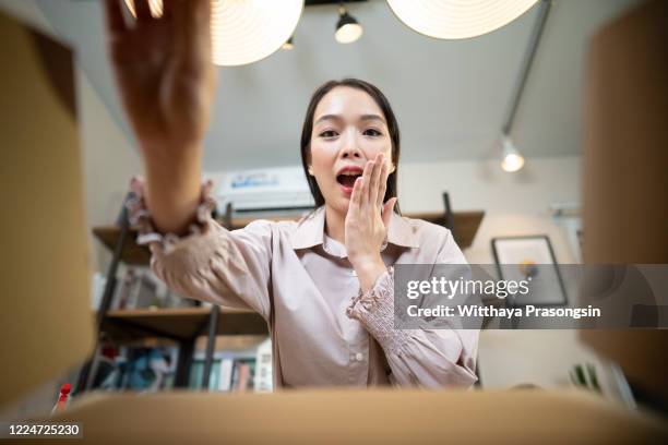 smiling woman opening a carton box - present unwrap stock-fotos und bilder