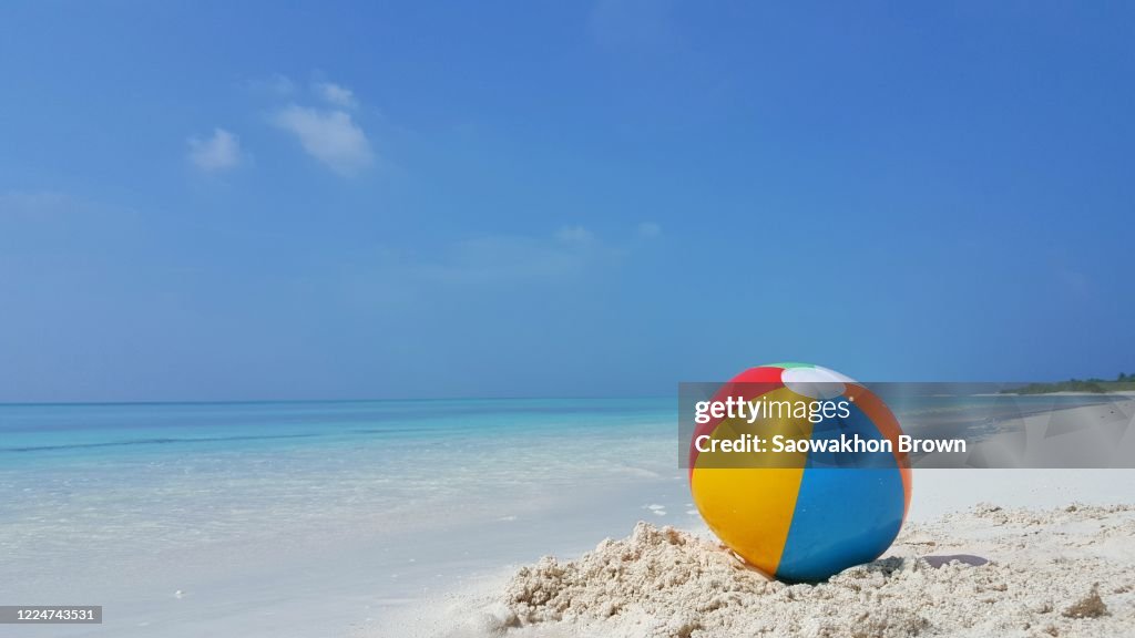 Beach ball on white sandy beach and beautiful tropical sea