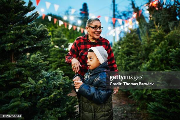 boy drinking hot chocolate while shopping for christmas tree with grandmother - winter jacket stock pictures, royalty-free photos & images