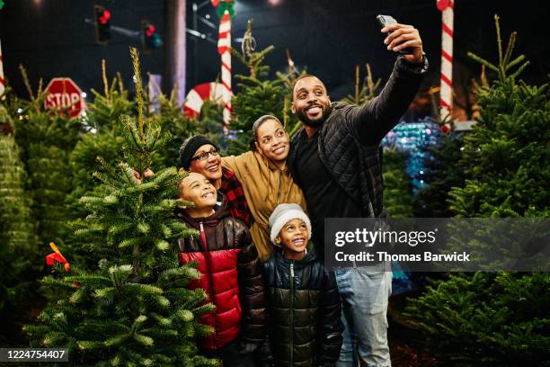 multigenerational family taking selfie while shopping for christmas tree - party or fashion or shopping or fun winter or chrismas or xmas or chrismas tree stock-fotos und bilder