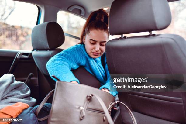 female driver searching for driver's license in handbag on car back seat - purse contents stock pictures, royalty-free photos & images