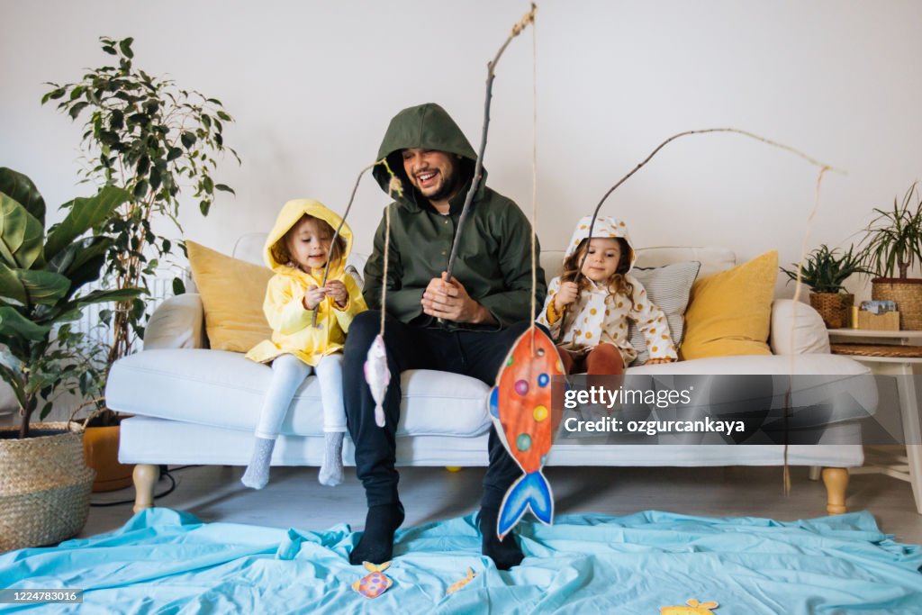 Crianças com o pai brincando de pescar em casa