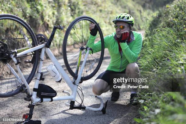 man looking at bicycle with damaged wheel - pierced stockfoto's en -beelden
