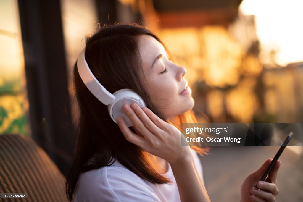 Close-up Shot Of Young Woman Enjoying Music Over Headphones And Using Smart Phone