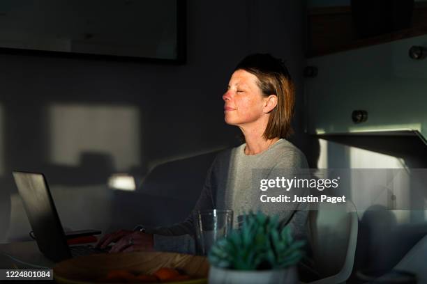 woman closing her eyes as the last sun rays of the day come into her house - andas in bildbanksfoton och bilder