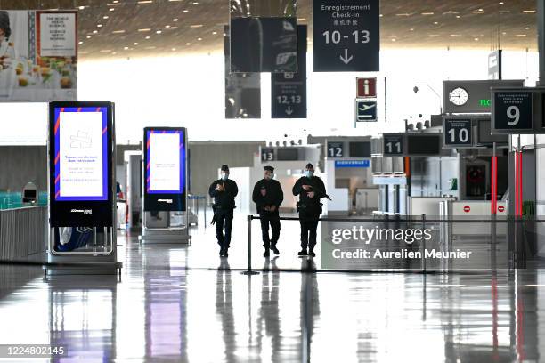 Police officers wearing face masks patrol at Roissy Charles De Gaulle airport during the Coronavirus 19) pandemic on May 14, 2020 in Paris, France....