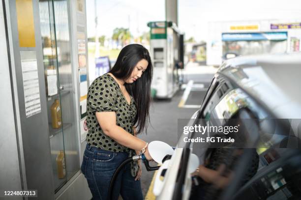 jonge vrouw die haar auto bijeentankt bij een benzinestation - gas tank stockfoto's en -beelden
