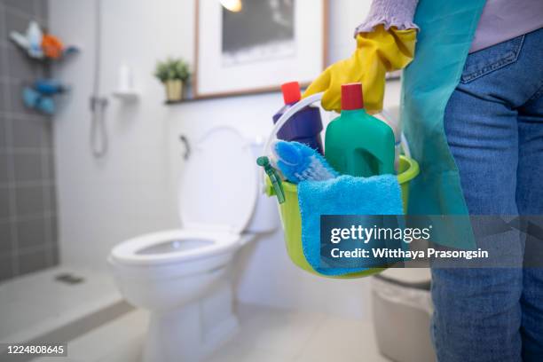 the cleaning woman is standing in the bathroom holding a blue bucket full of chemicals and facilities for storing her hands. - clean bathroom stock pictures, royalty-free photos & images