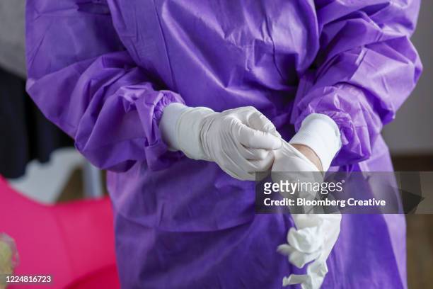 a doctor in a surgical gown and gloves - purple glove stock pictures, royalty-free photos & images