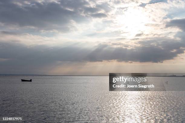 einsames boot auf dem meer - dramatischer himmel stock pictures, royalty-free photos & images