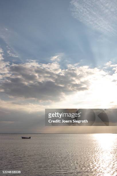 einsames boot auf dem meer - wolkengebilde stockfoto's en -beelden