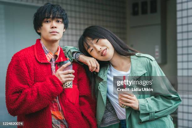 joven pareja asiática o amigos con bubble tea mirando la cámara - abrigo verde fotografías e imágenes de stock