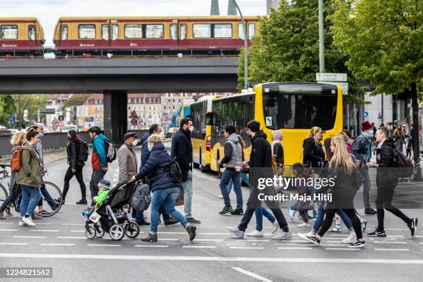 People wear protective masks as they cross the street near Alexanderplatz on May 14 in Berlin, Germany. As authorities continue to ease lockdown...