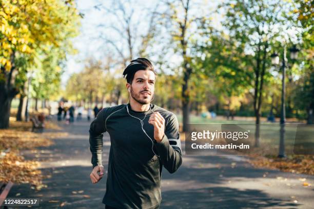 young man jogging in the city park - running stock pictures, royalty-free photos & images