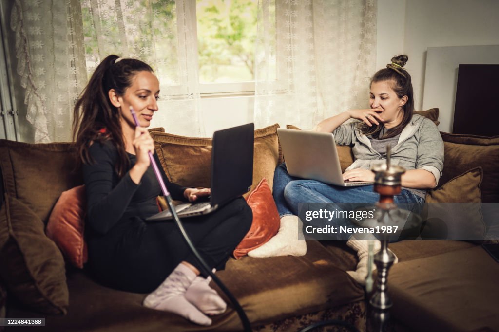 Two young female friends using laptop