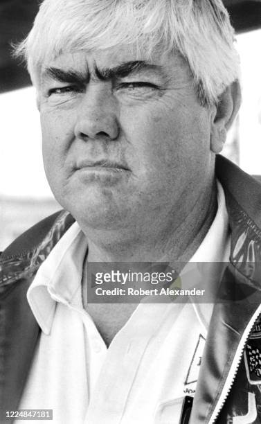 Veteran NASCAR driver and car owner Junior Johnson watches race cars circle the speedway during a practice session prior to the start of the 1984...