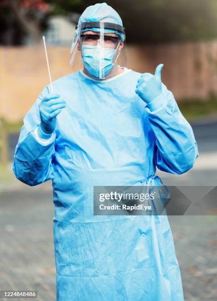 doctor, nurse or laboratory worker with swab for administering coronavirus covid-19 test - operating gown stock pictures, royalty-free photos & images