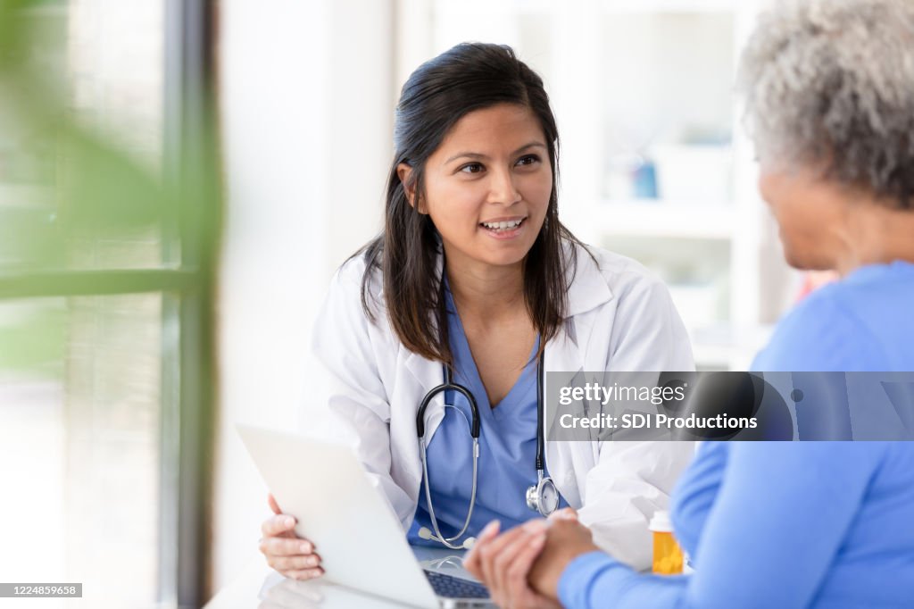 Kvinnlig patient lyssnar noga på mellan vuxen kvinnlig läkare