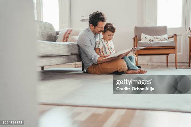 familie liest ein buch - dad and son stock-fotos und bilder