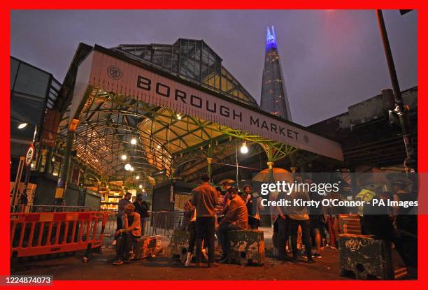 The Shard is lit blue in honour of the NHS as people are out in Borough Market, London, as coronavirus lockdown restrictions are eased across England.