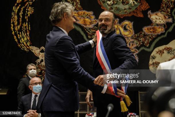 Le Havre outgoing mayor Jean-Baptiste Gastinne adjusts the mayor scarfs of his successor, French former Prime Minister Edouard Philippe , after he...
